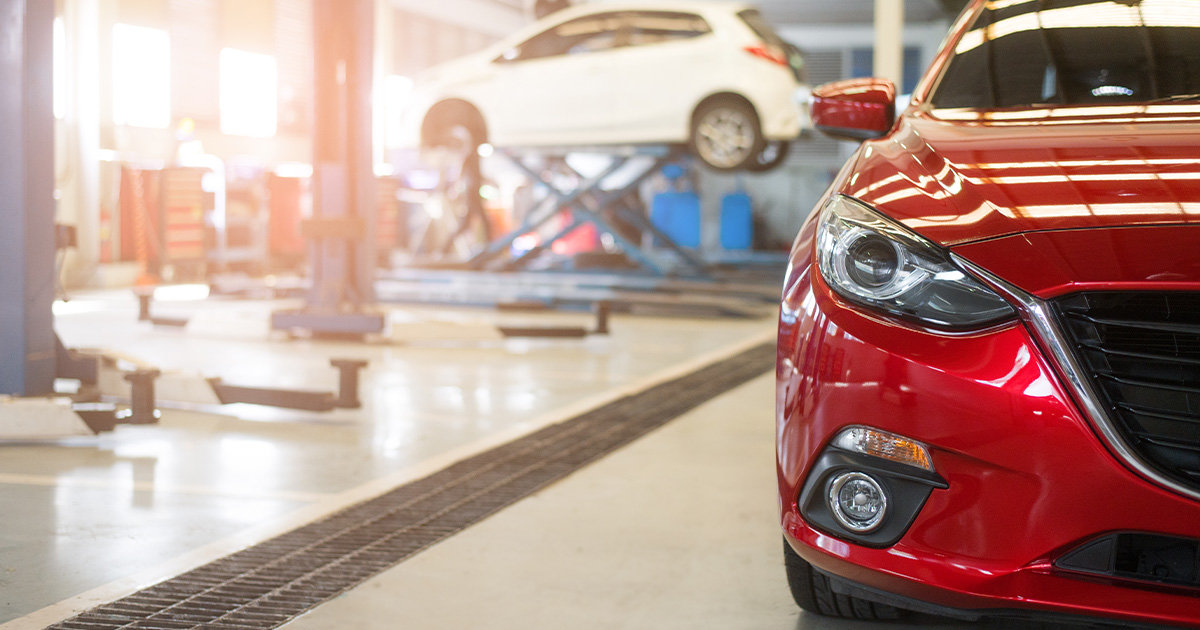 Automotive shop, close-up of a red car with flooring and other cars in the background.